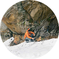 Advanced Wilderness Survival. Picture of a man making a fire in the snow.